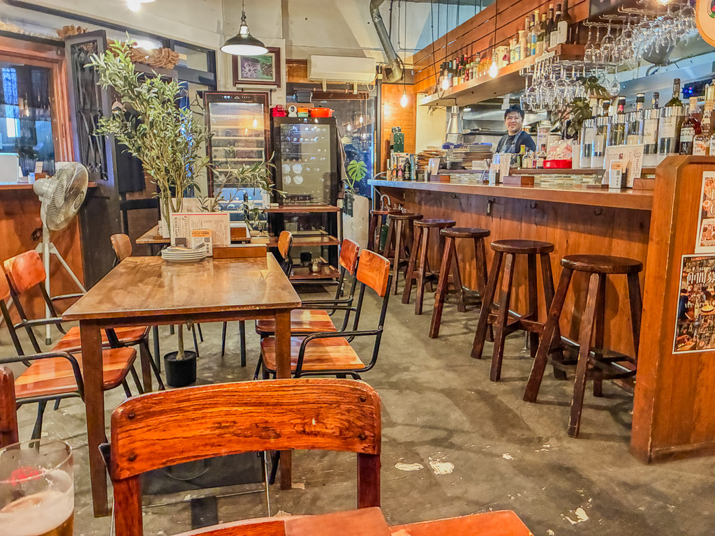 ALGOS DELI×HAMBURG（アルゴス デリ×ハンバーグ）店內 — 木質吧檯與整排紅酒瓶的開放式廚房