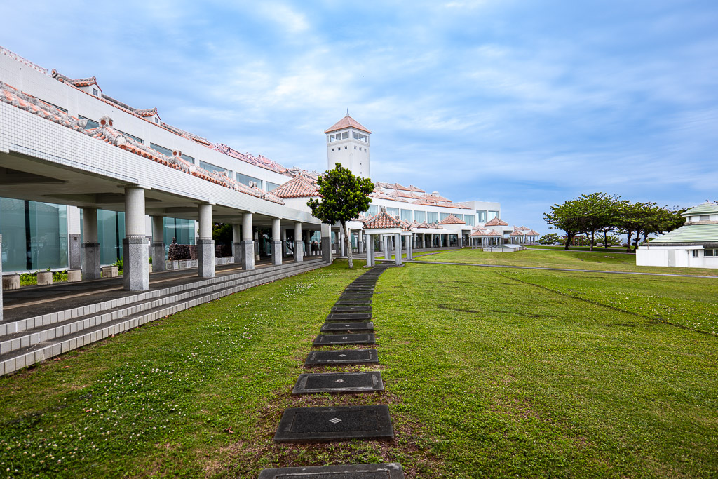 沖繩平和祈念資料館側面迴廊與平和祈念堂白色塔 — 草地庭園
