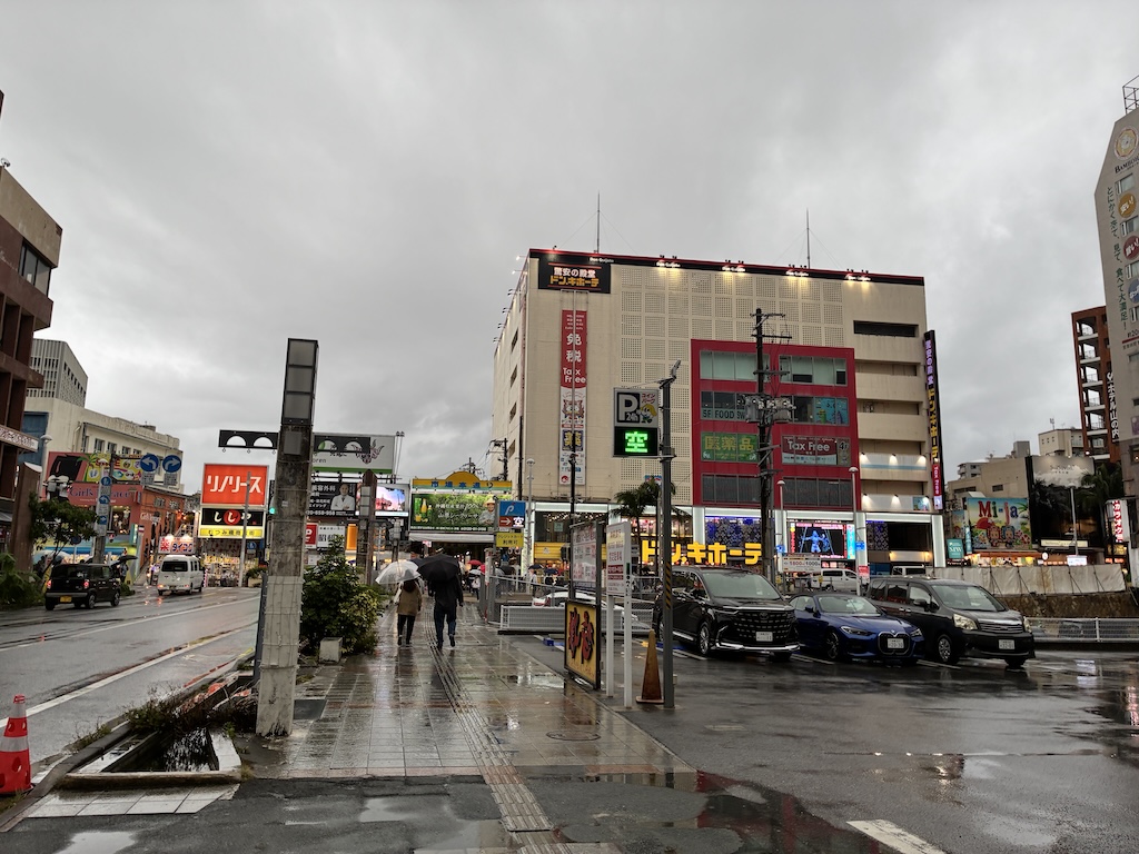 沖繩那霸街頭雨天景象，遠處可見唐吉訶德與停車場大樓——用日本eSIM隨時查交通與避雨景點