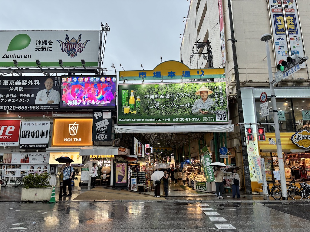 沖繩那霸市場本通入口街景，有日語廣告招牌與KOI Thé——日本eSIM協助即時翻譯與找路