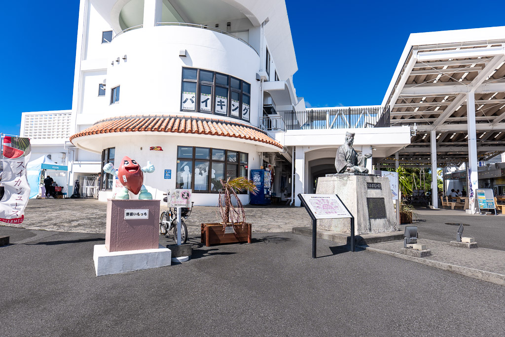 道之驛嘉手納圓弧造型自助餐廳建築前的野國總管銅像與番薯吉祥物野國いもっち