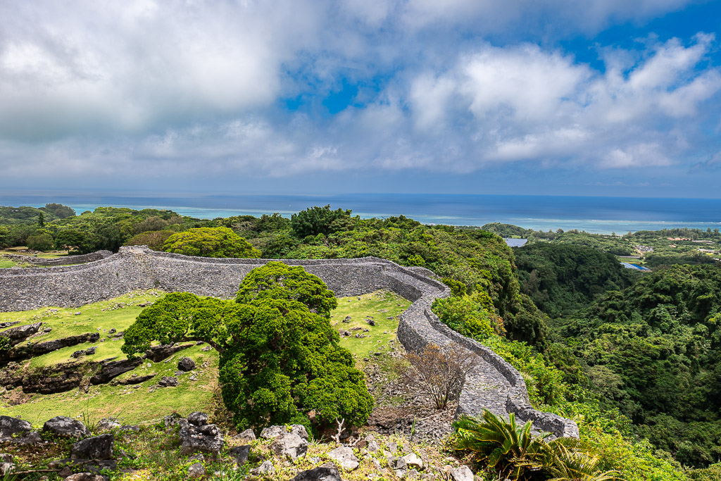 沖繩今歸仁城跡曲線石垣延伸至遠方翠綠山林與蔚藍海景